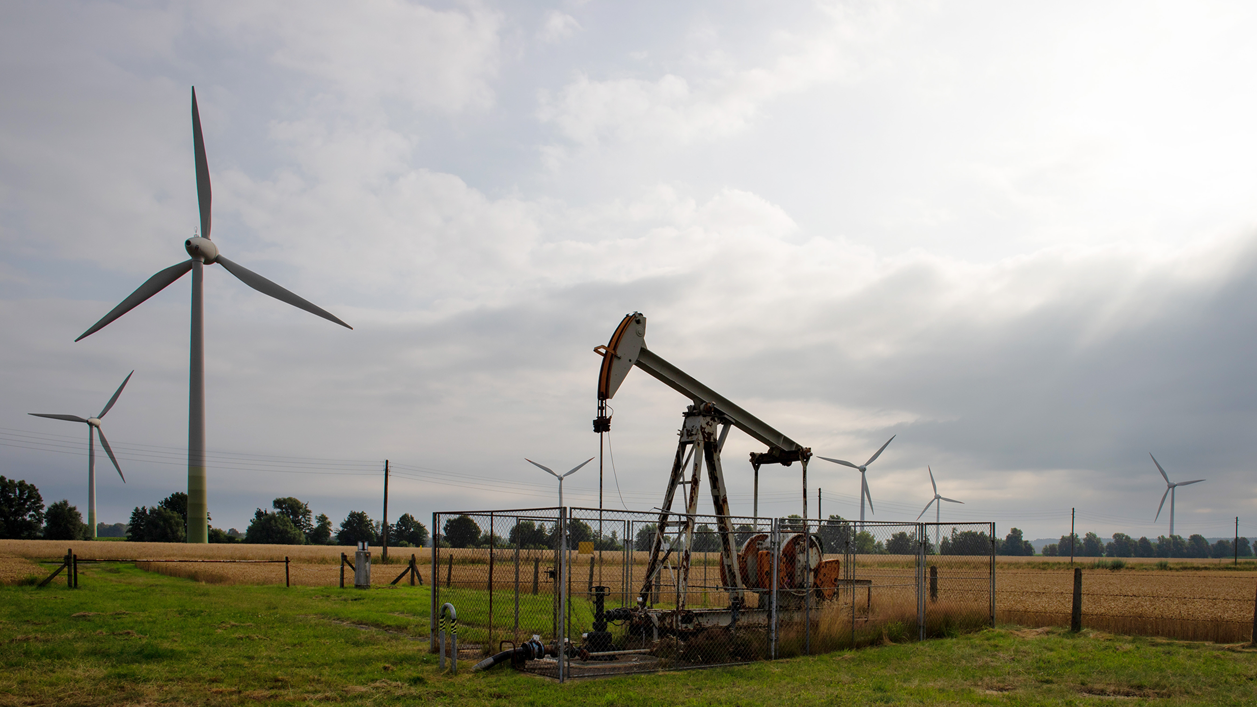 Photo shows energy windmills and an oil pumpjack near each other in a landscape